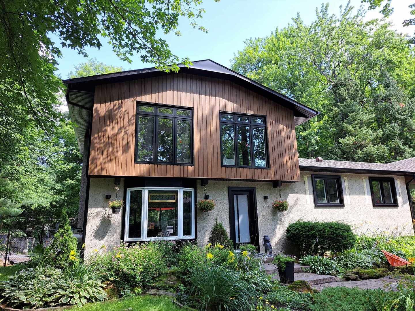 Une grande maison avec beaucoup de fenêtres est entourée d'arbres.