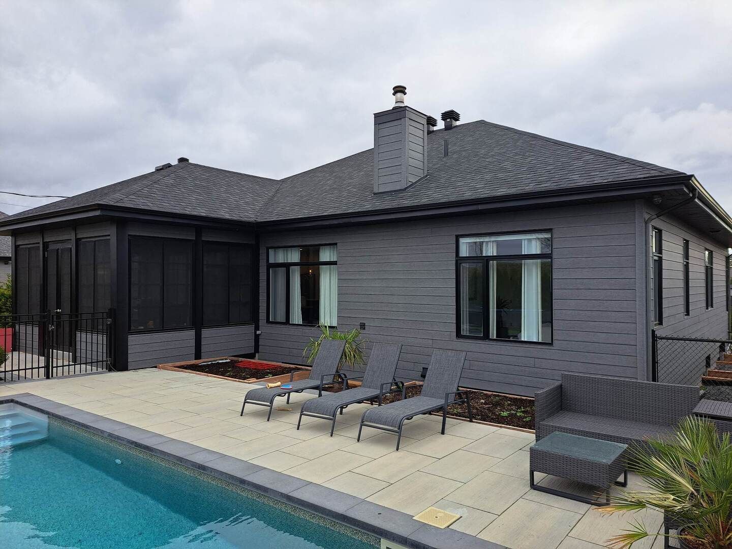 Une maison grise avec une piscine devant.