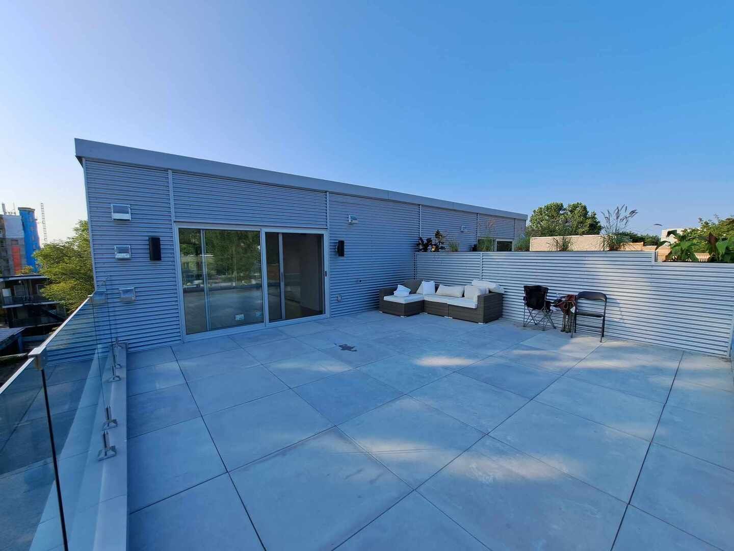 Une terrasse sur le toit avec un canapé et des chaises dessus.