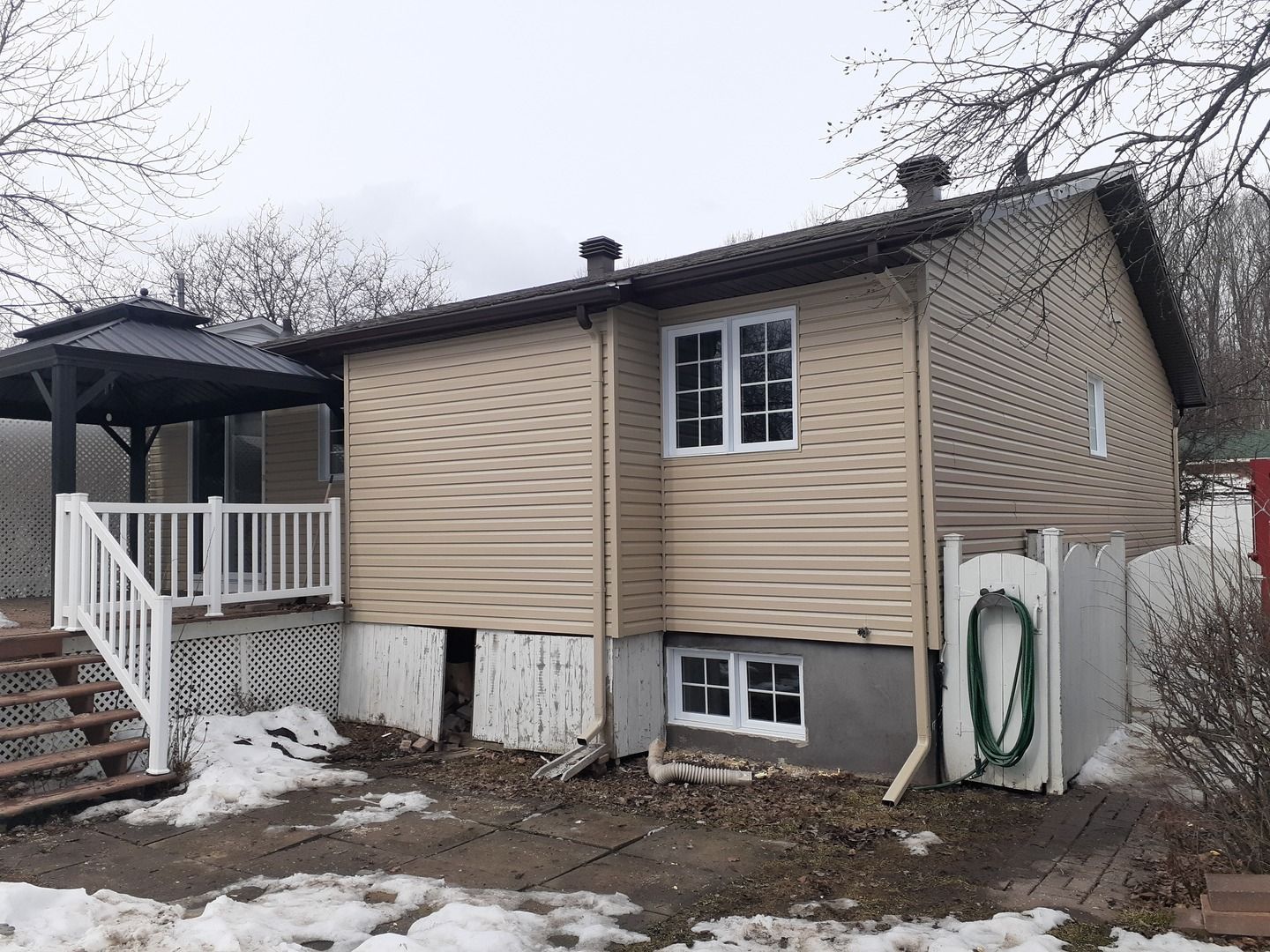 Une petite maison avec un porche et des escaliers dans la neige.