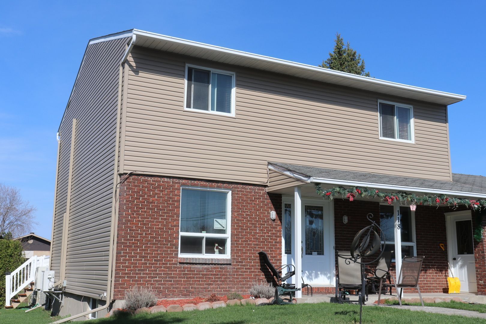 Une grande maison en briques avec un porche et des chaises devant.