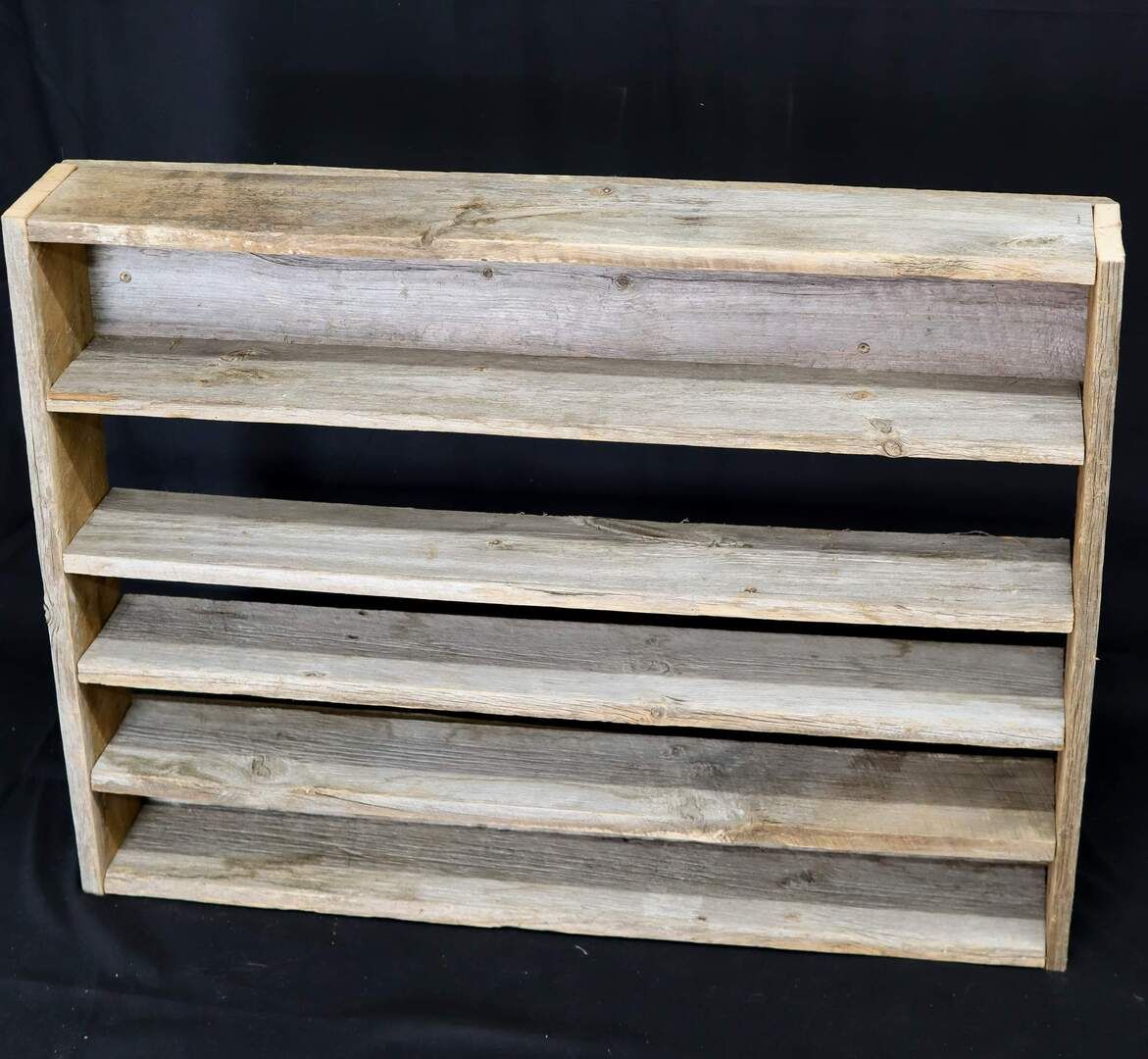 A wooden shelf is against a black background