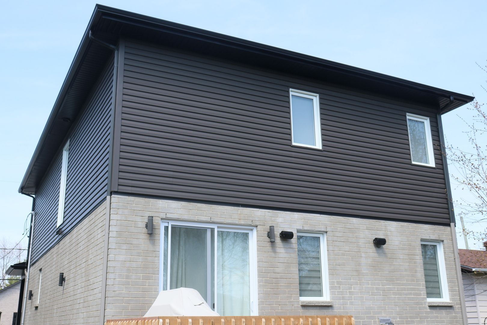 Une grande maison en briques avec un revêtement marron et des fenêtres blanches.