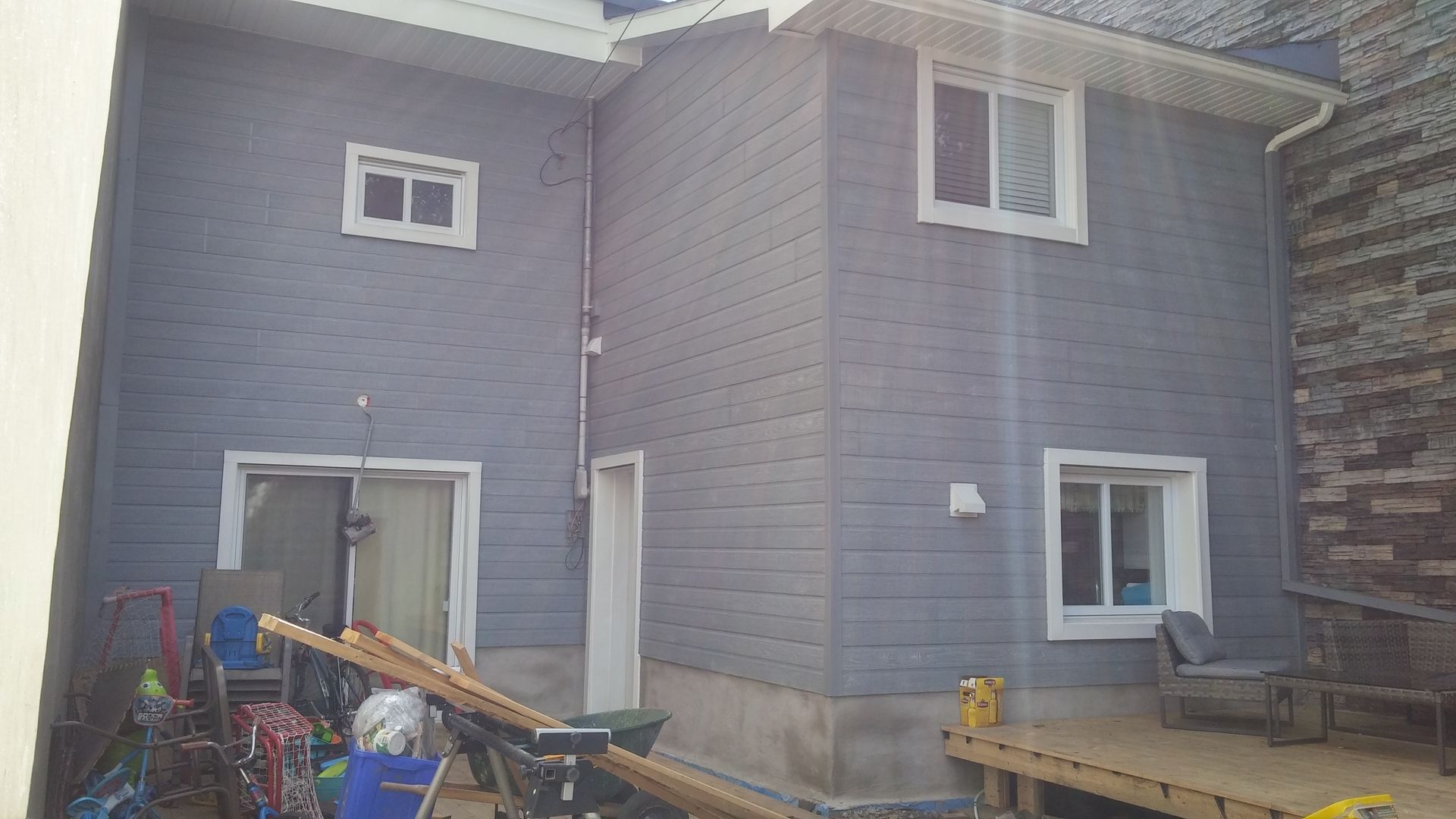 Une maison avec beaucoup de fenêtres et une terrasse devant.