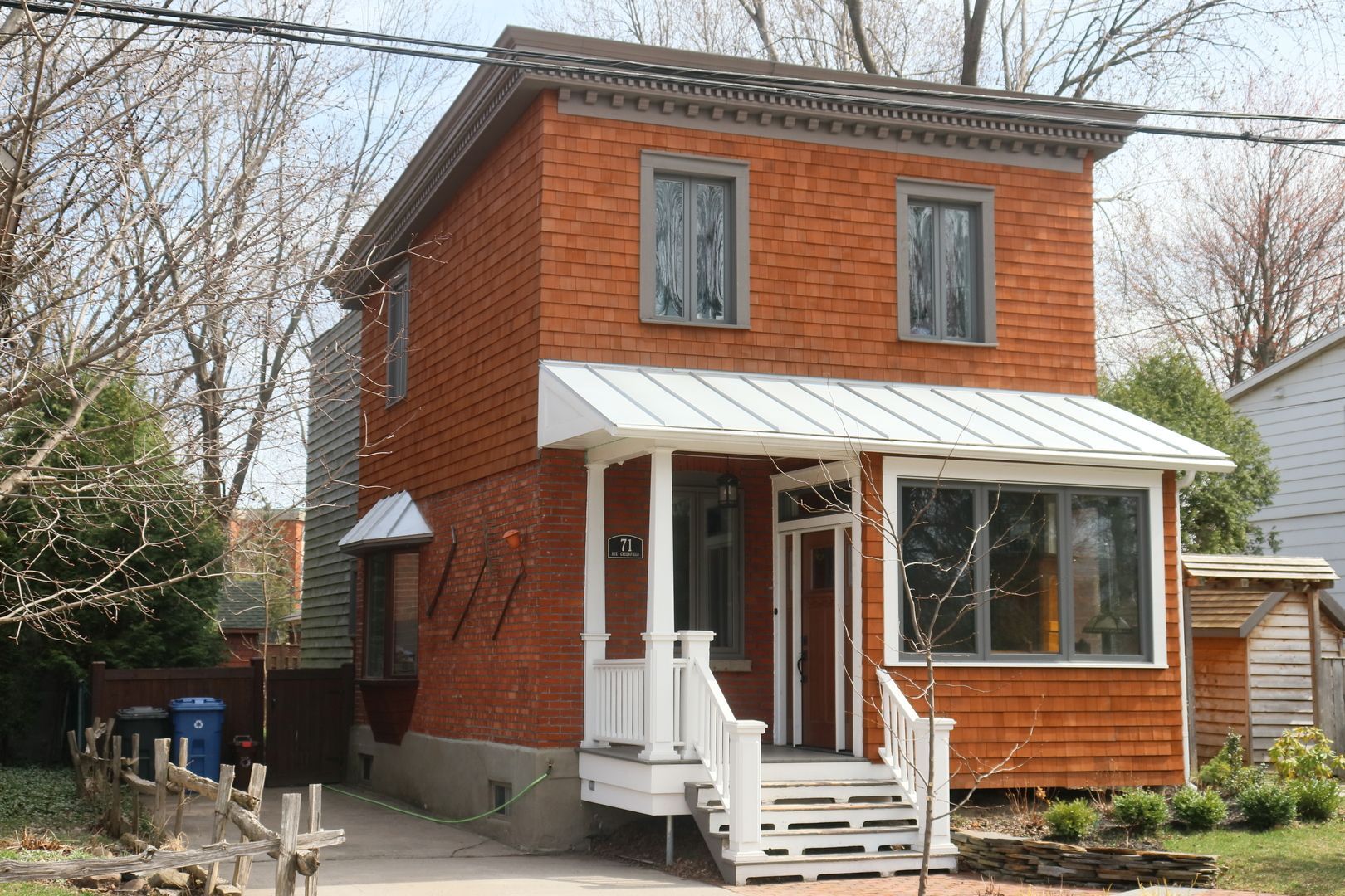 Une petite maison en briques avec un porche blanc et des escaliers