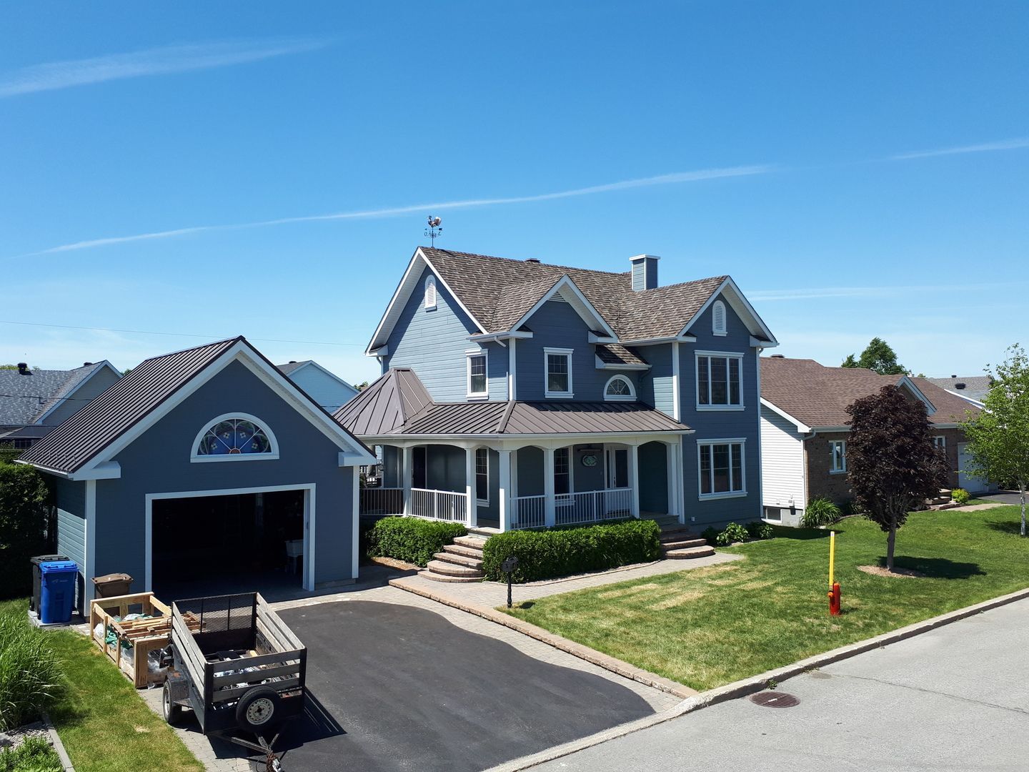 Une grande maison bleue avec un garage et une caravane garée devant