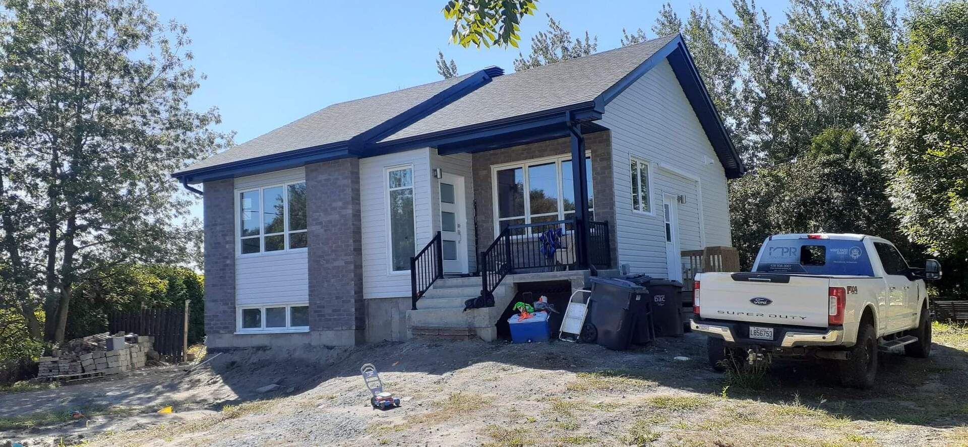 Un camion blanc est garé devant une petite maison.