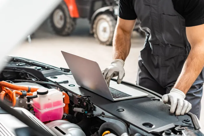 Mechanic using laptop to diagnose a car engine, hands in gloves | 1st Choice Autoworks