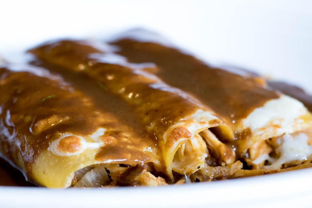 Chicken enchiladas covered in brown sauce, close-up.