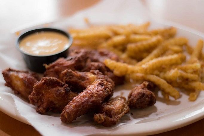 Plate with fried chicken wings, crinkle-cut fries, and dipping sauce.