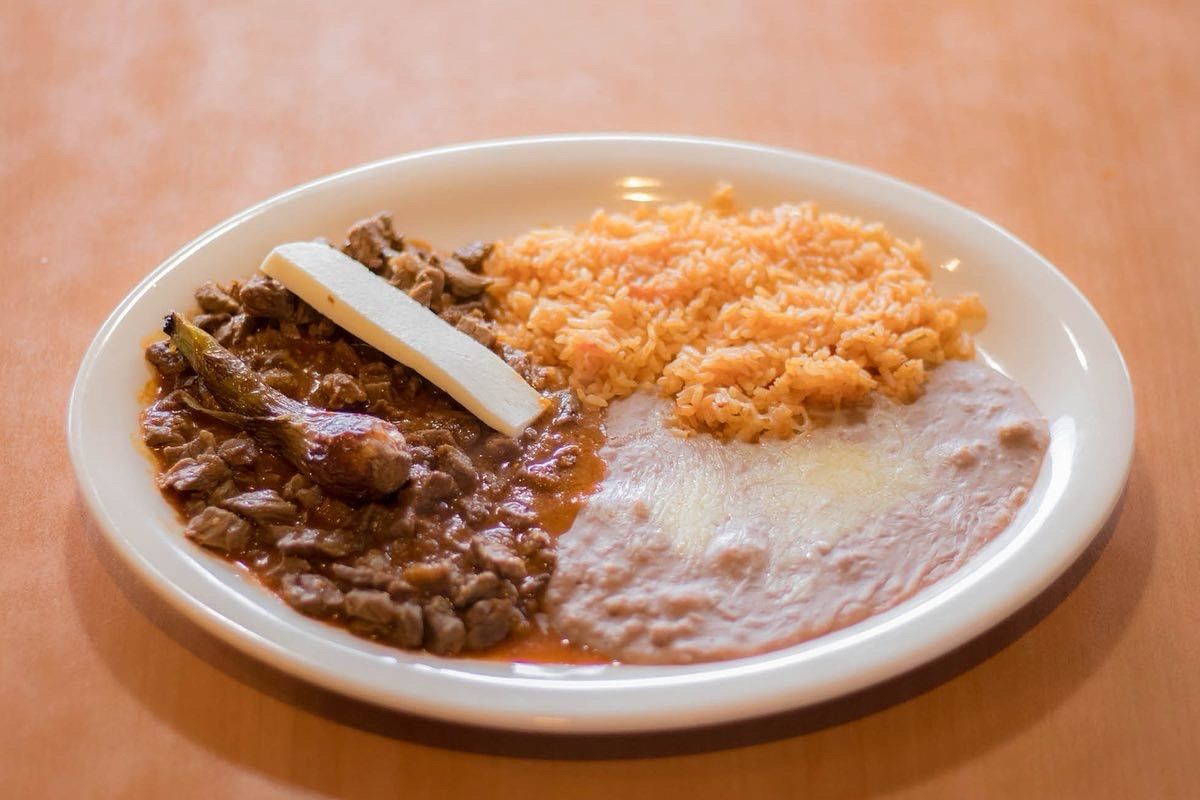 Plate with beef in sauce, rice, beans, and a slice of cheese.