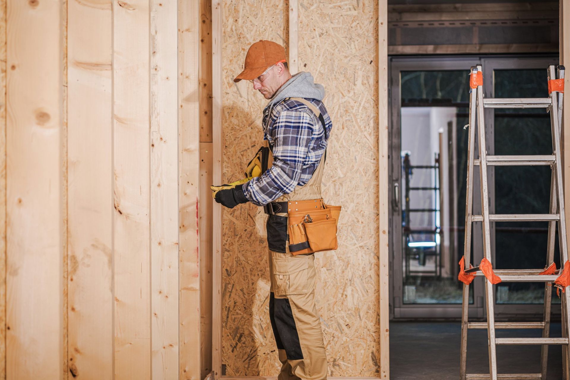 Construction worker using a tool to measure wood paneling inside a building.
