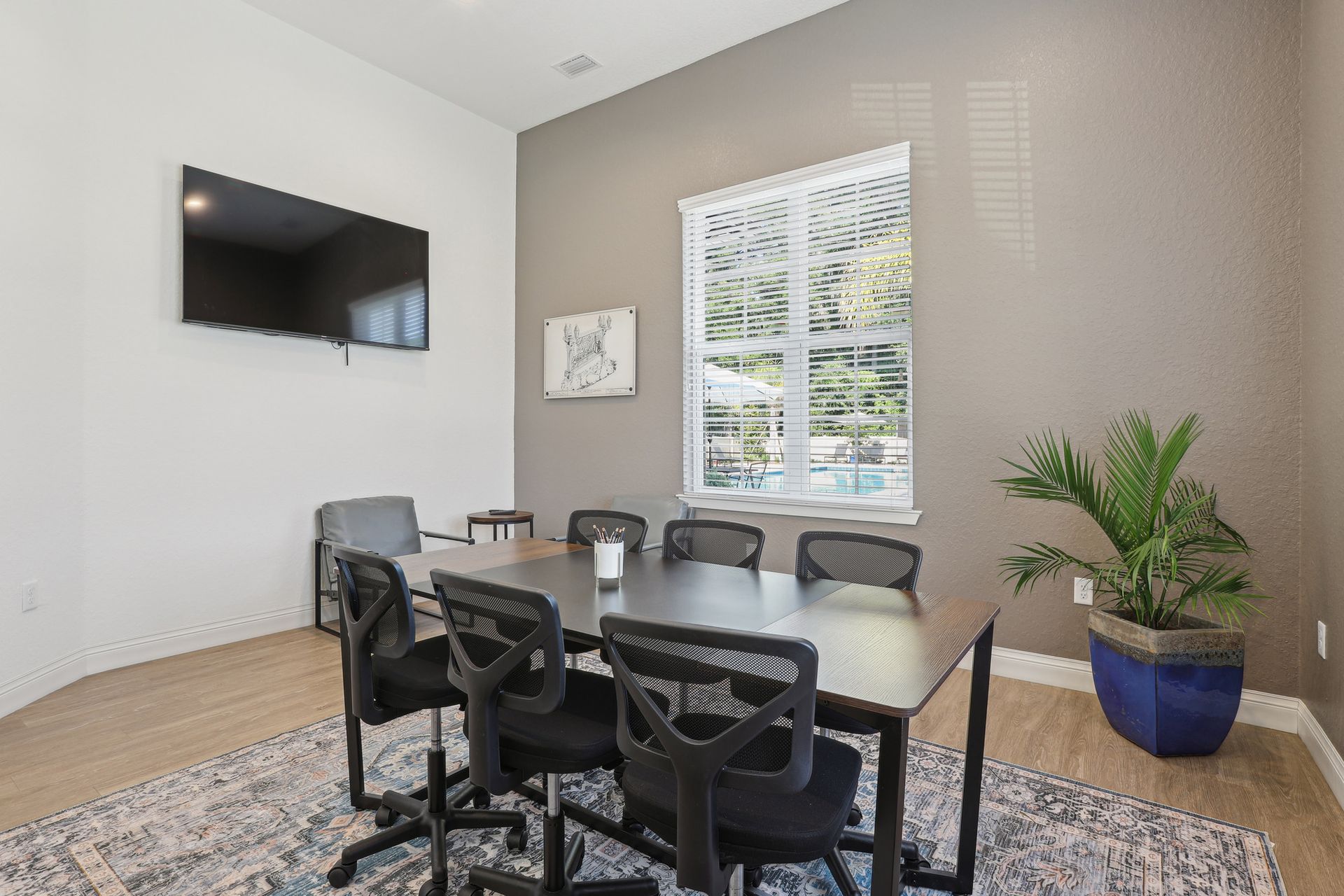 Conference room with table, chairs, TV, and plant.