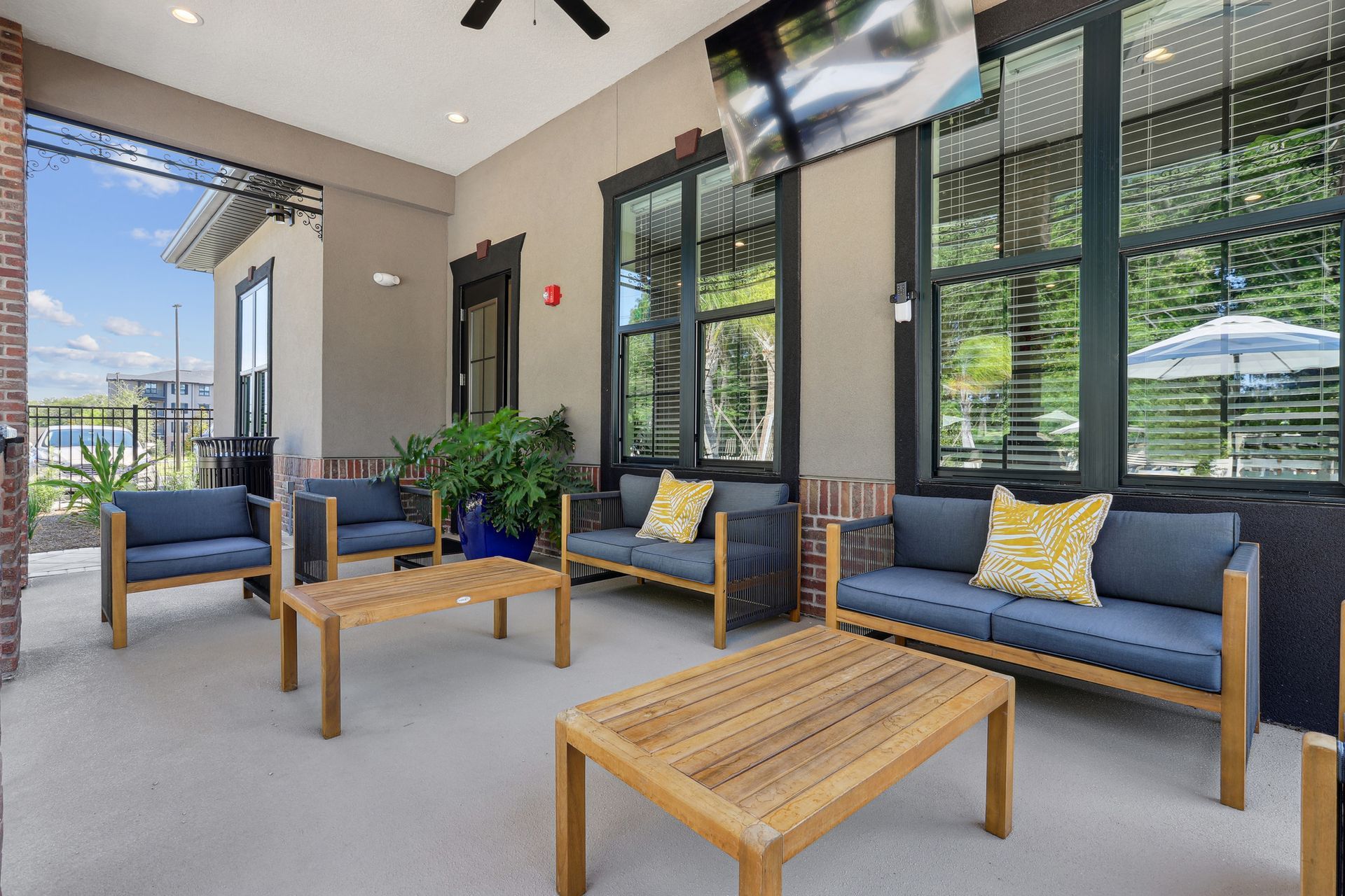 Outdoor patio with wood furniture, gray cushions, and a mounted TV.