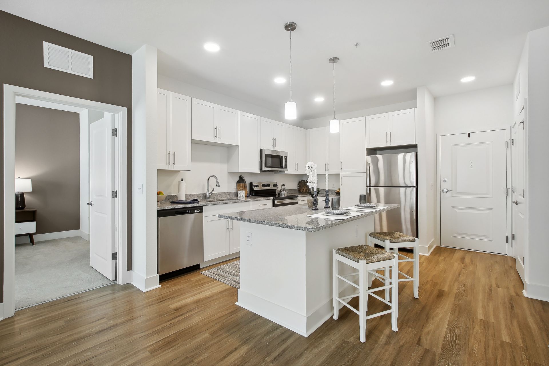 Modern kitchen with white cabinets, stainless steel appliances, and a small island with stools.