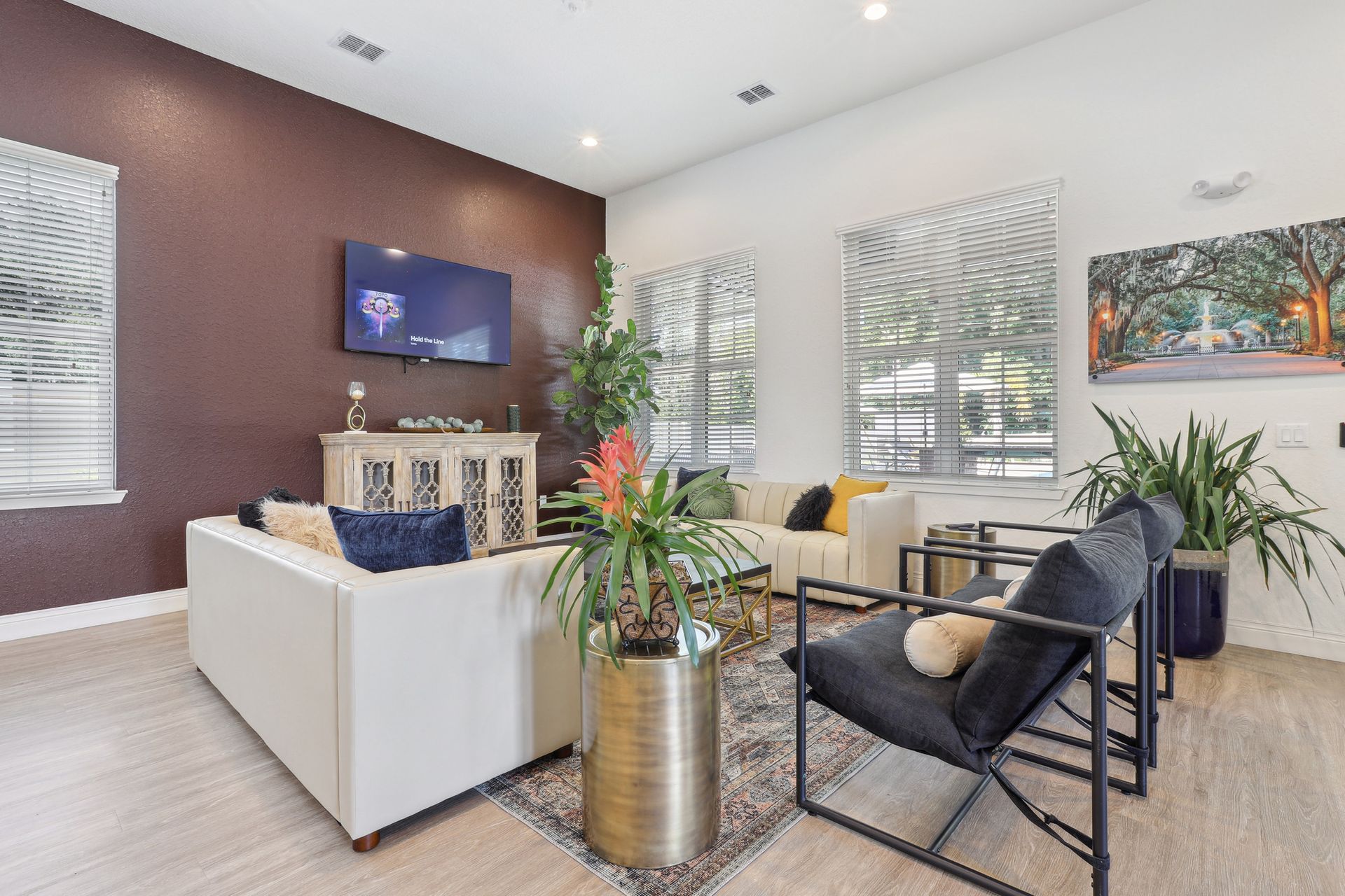 Modern living room with a white couch, dark accent wall, and potted plants.