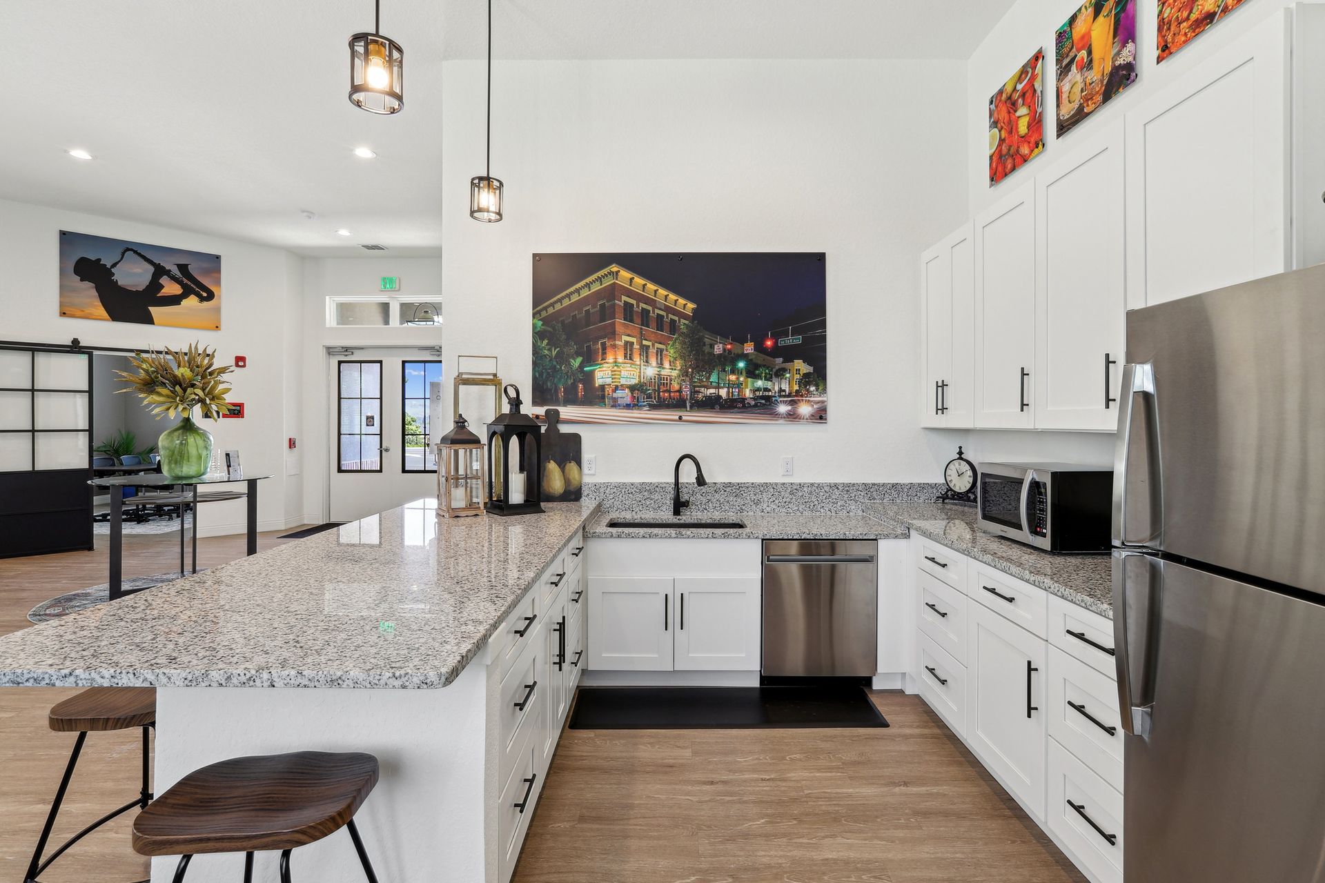 Kitchen with white cabinets, granite countertops, stainless steel appliances, and art.