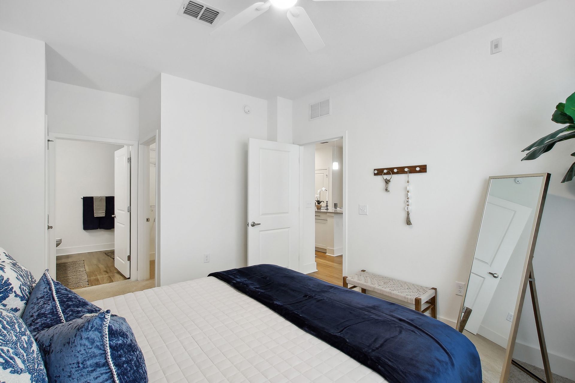 Bedroom with a bed, mirror, and doors to bathroom, painted white, with navy blue accents.