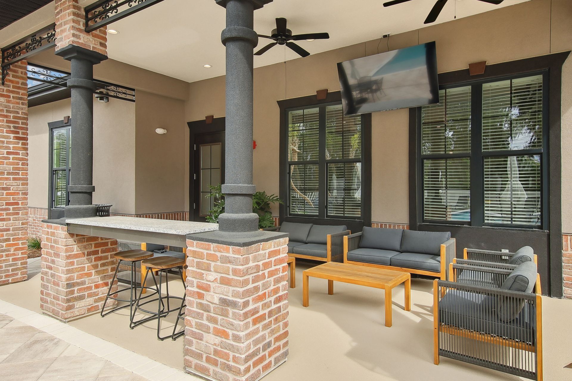 Outdoor patio with seating, bar, TV, and brick columns.
