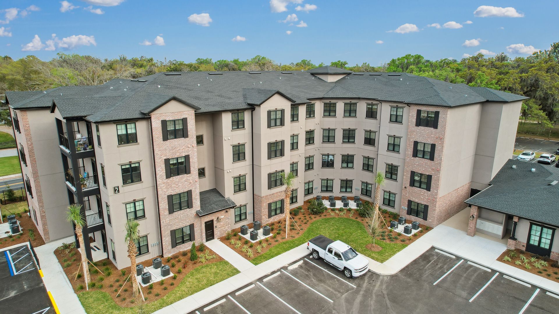 Exterior view of a multi-story apartment building with a parking lot in front.