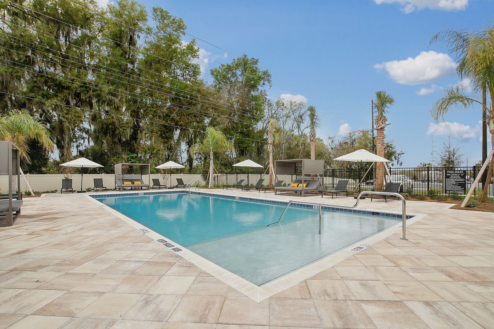 Swimming pool with umbrellas and lounge chairs on a sunny day.