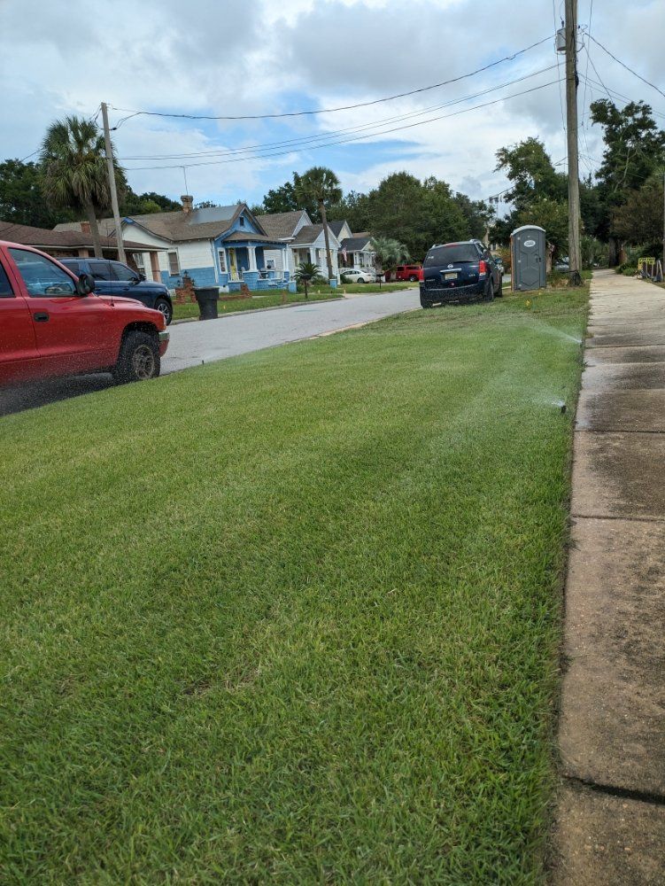 Suburban street with a red pickup, black SUV, grassy verge, and portable toilet on the sidewalk