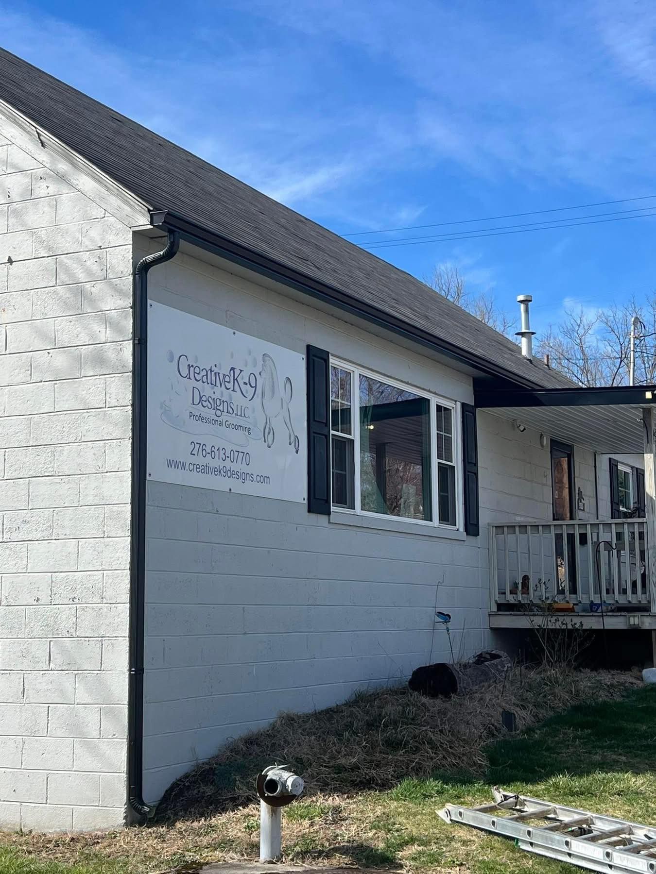 A white brick building with a sign featuring hands in prayer, with a small wooden porch and a blue sky in the background.