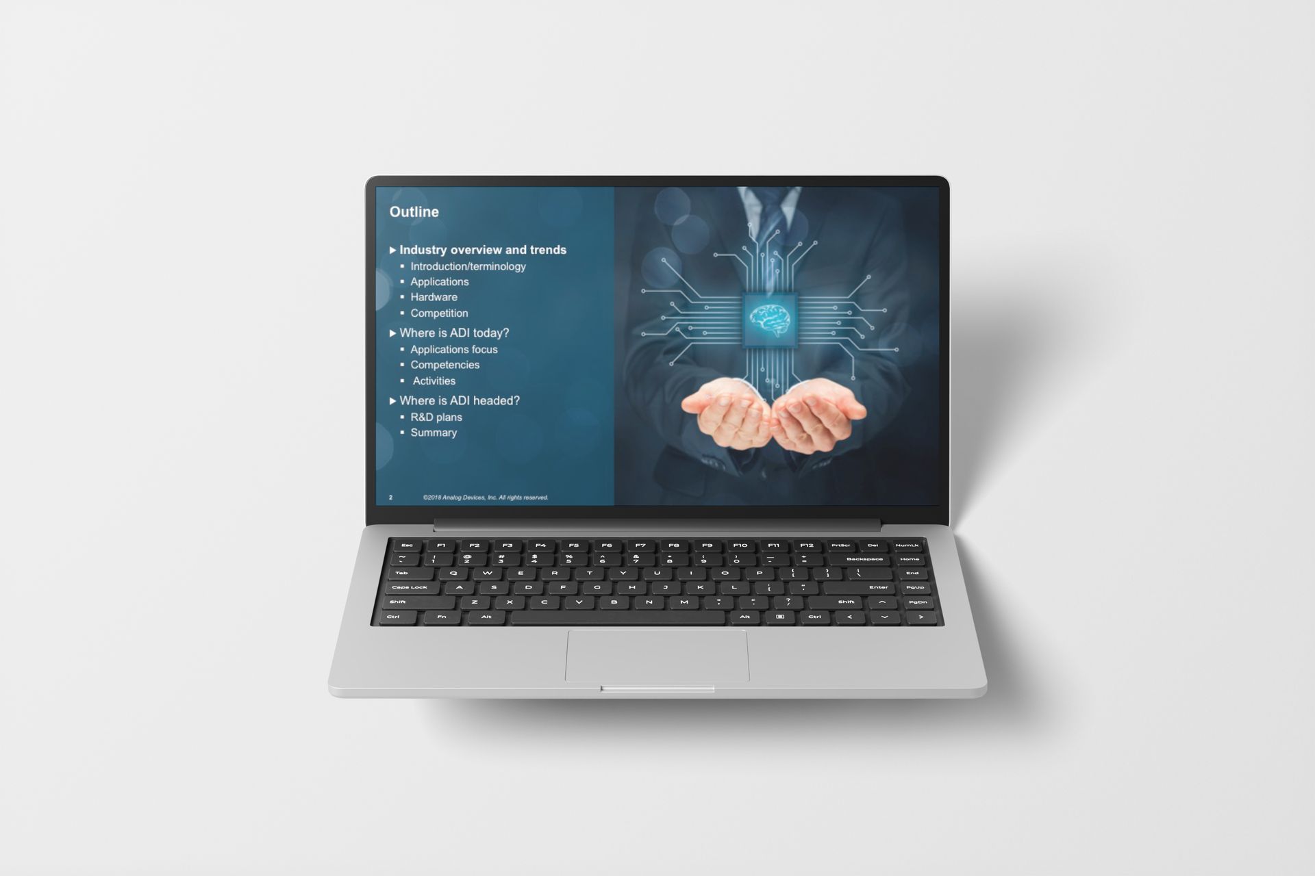 Laptop displaying a presentation on a white surface, featuring a brain graphic held by hands.