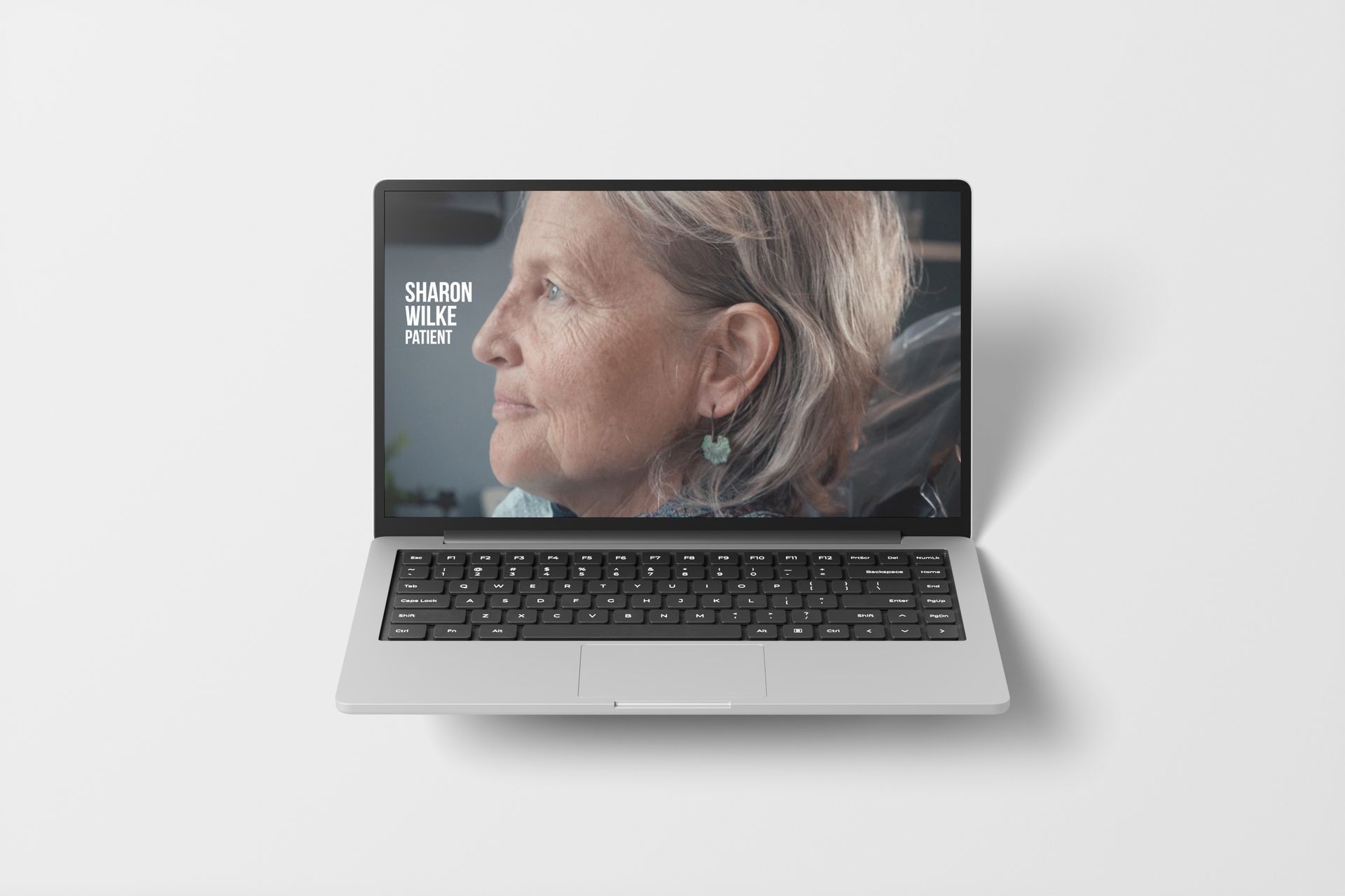 Laptop displaying a video of a woman. A logo is visible on the left side of the screen.