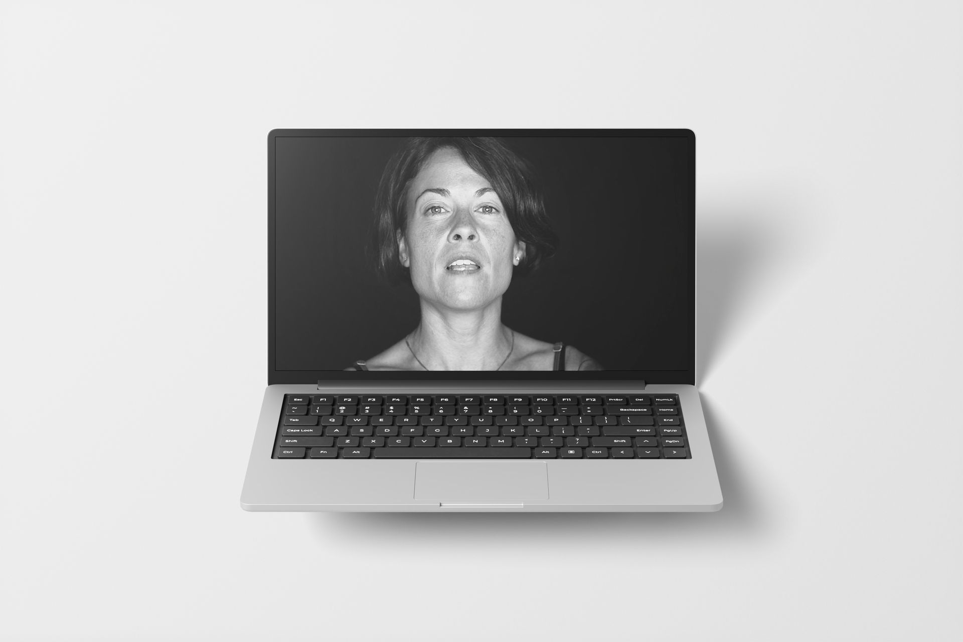 Laptop displaying a black and white photo of a woman with a surprised expression.