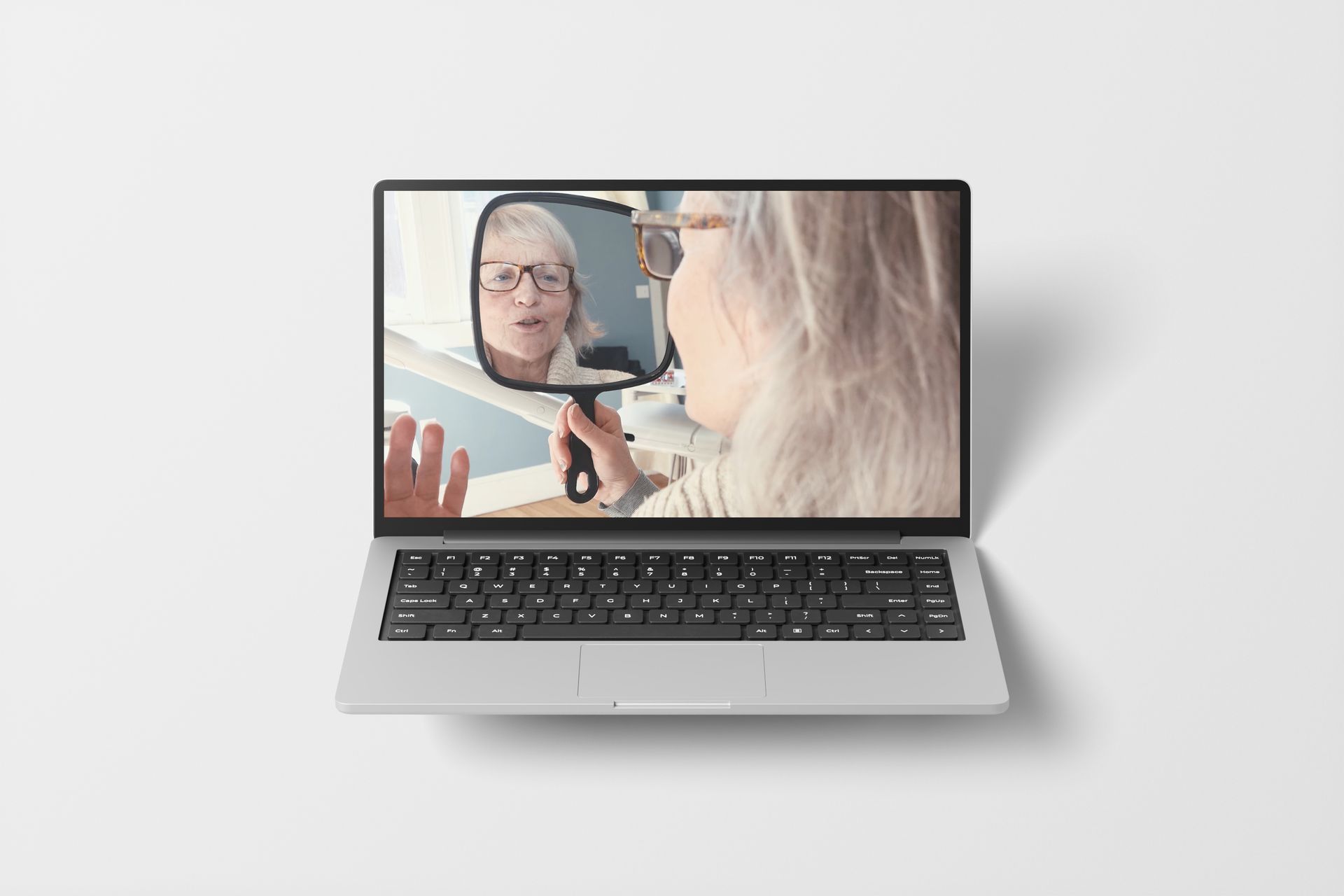 Laptop displaying a video call of a woman holding a mirror.