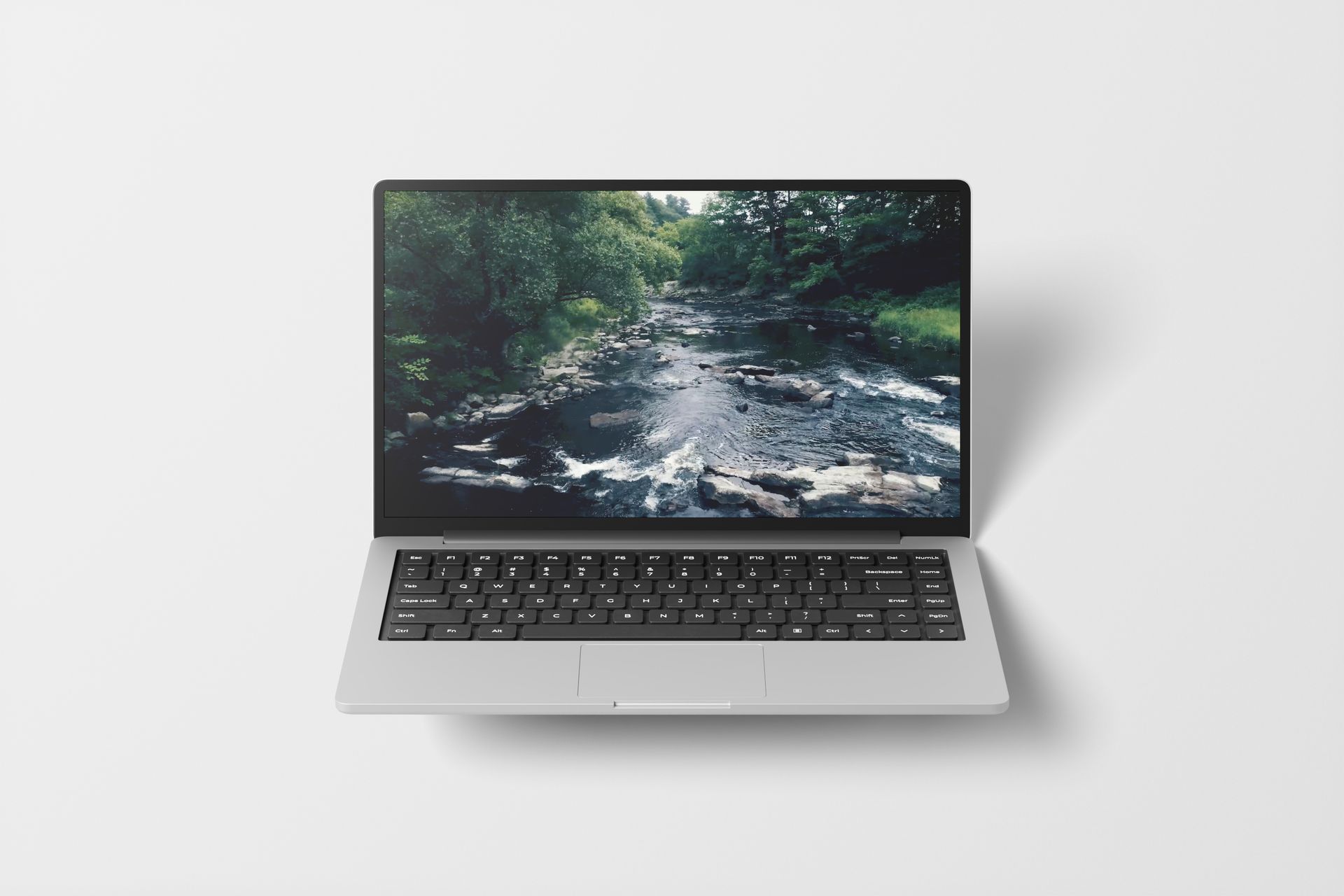 Silver laptop displaying a stream scene, open on white surface.