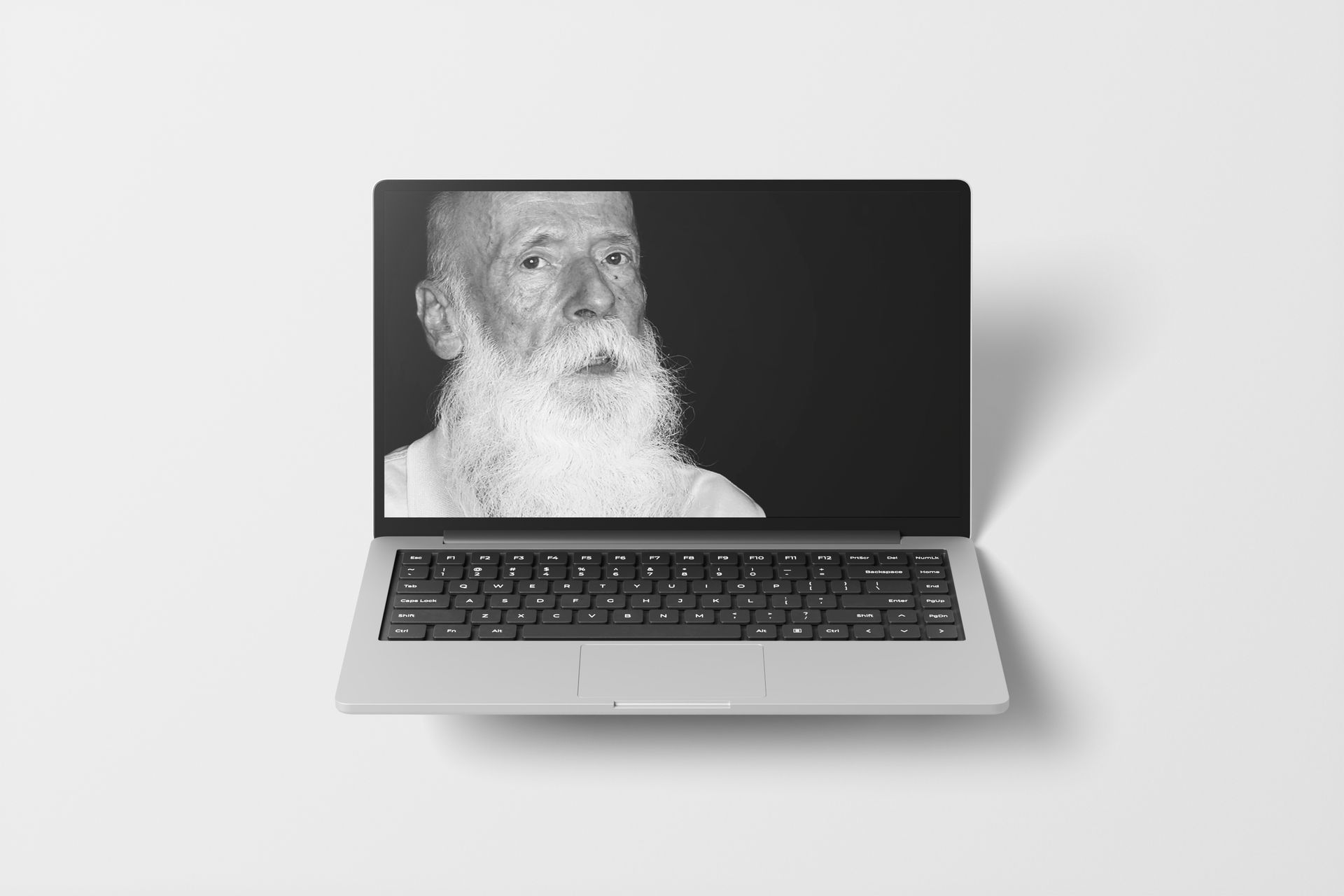 Laptop displaying a black-and-white portrait of an older person with a long, white beard.