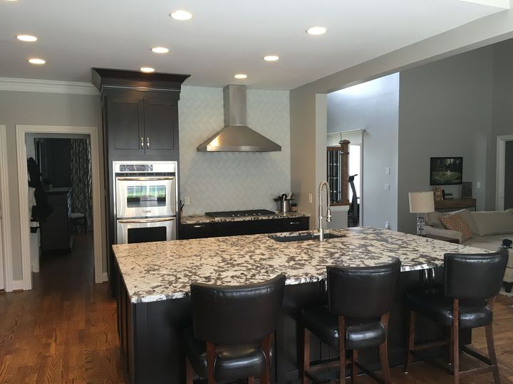 a kitchen with granite counter tops and black chairs