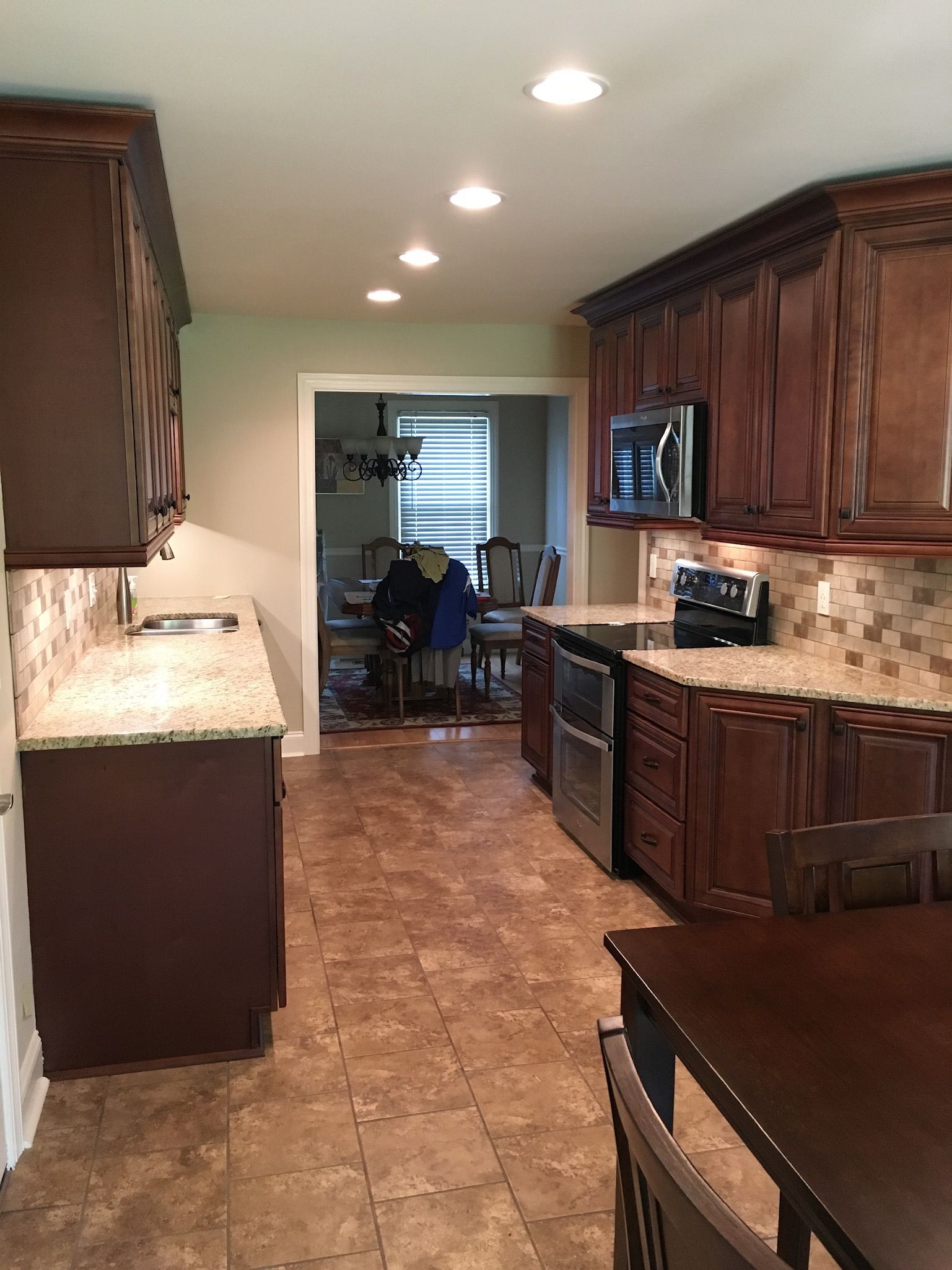 a kitchen with wooden cabinets, granite counter tops, a table, and chairs
