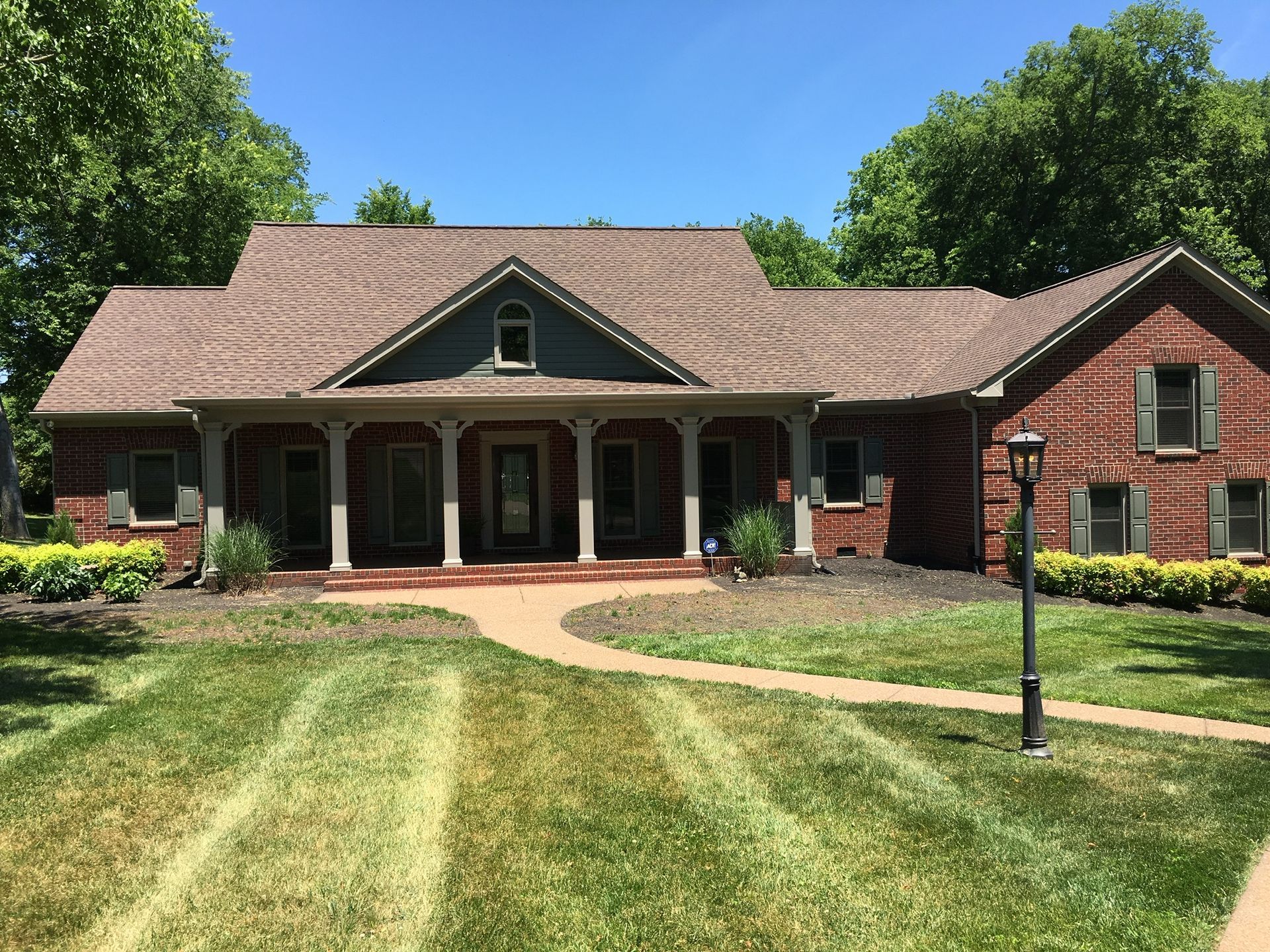 a large brick house with a porch and a lush green lawn