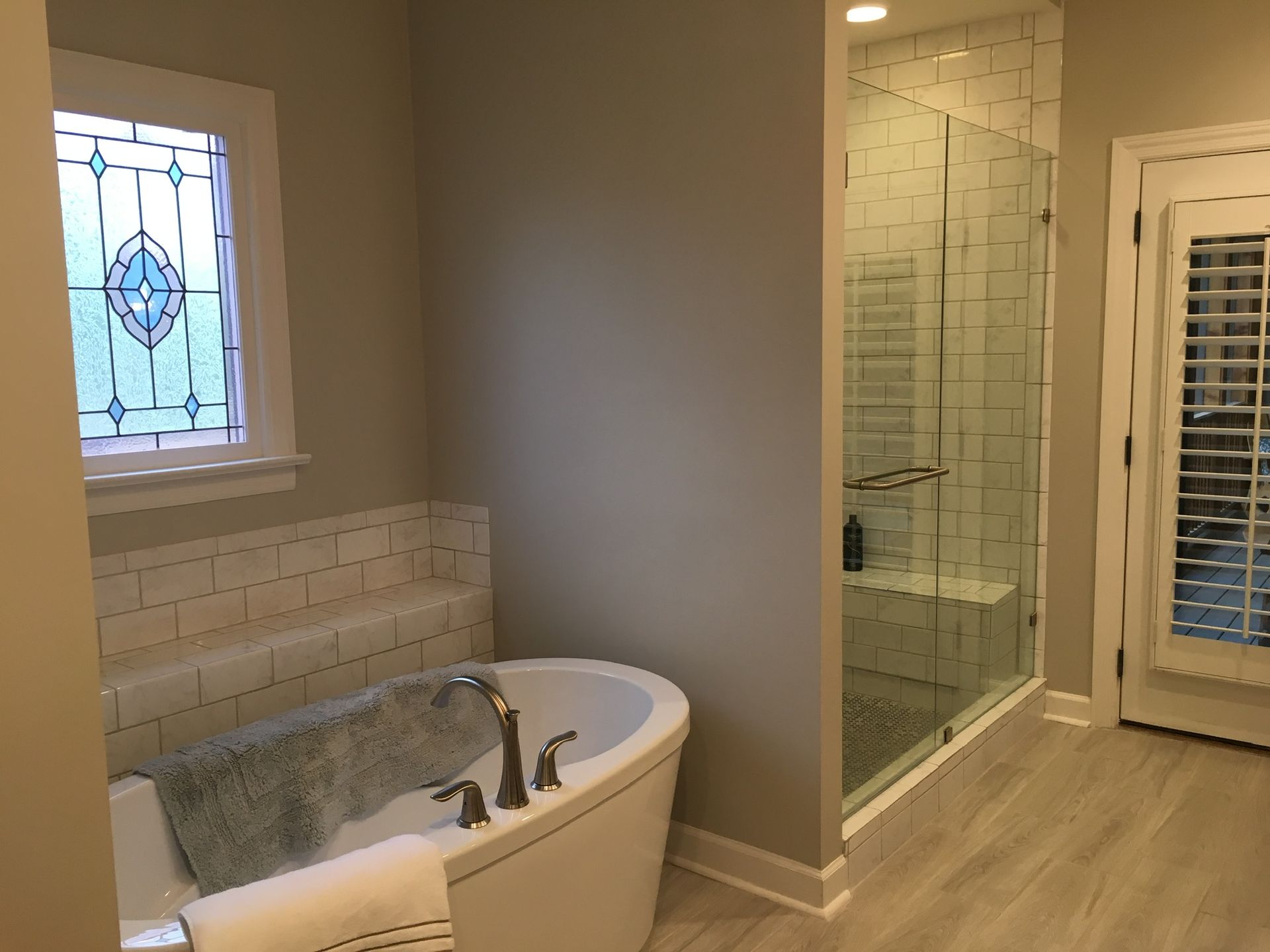 a bathroom with a tub , shower and stained glass window