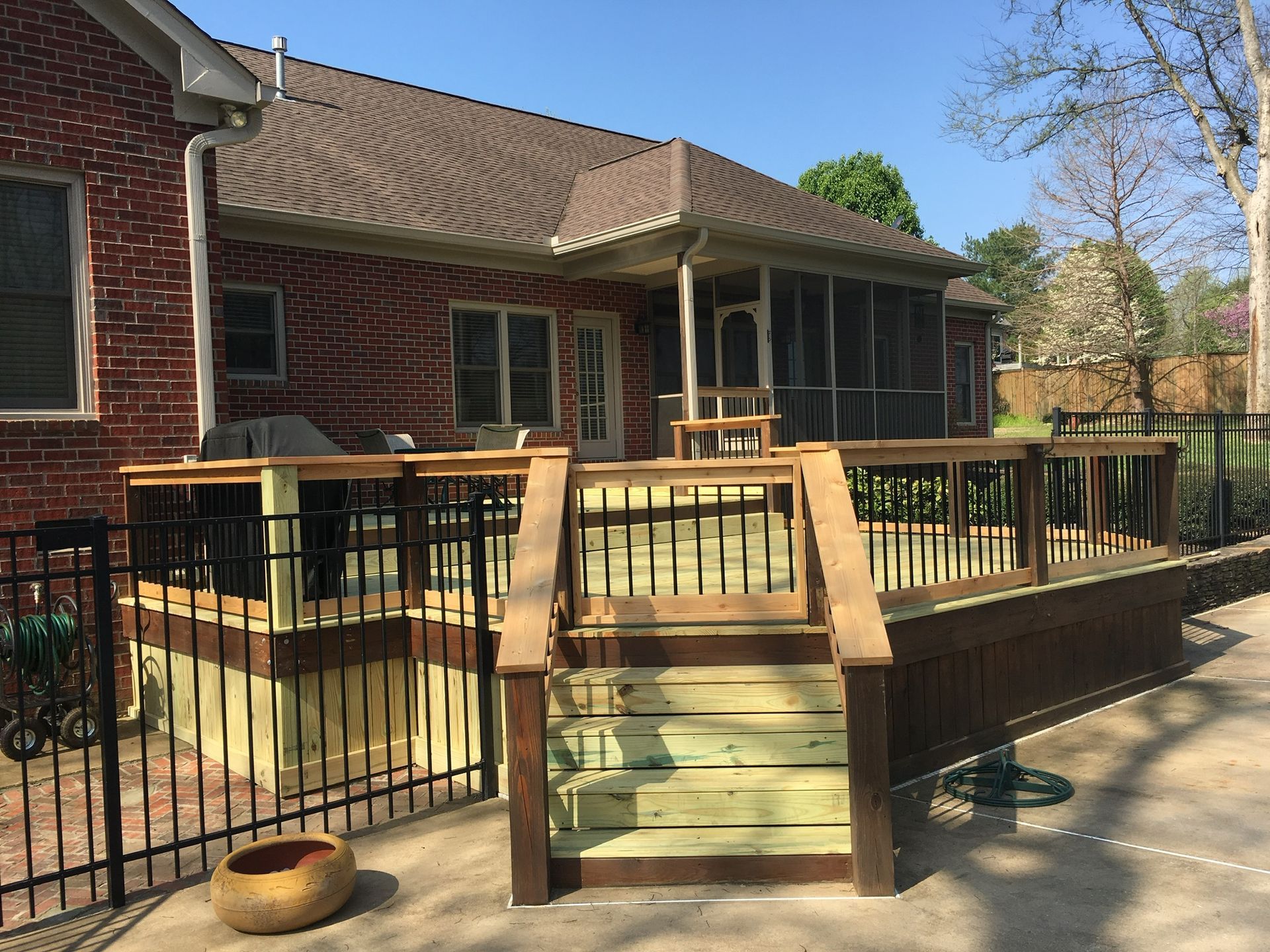a brick house with a screened in porch and a wooden deck