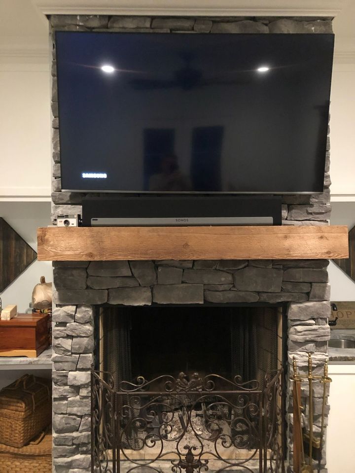 a flat screen tv is mounted above a fireplace in a living room