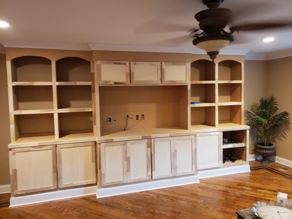 a living room with a ceiling fan and lots of shelves and cabinets