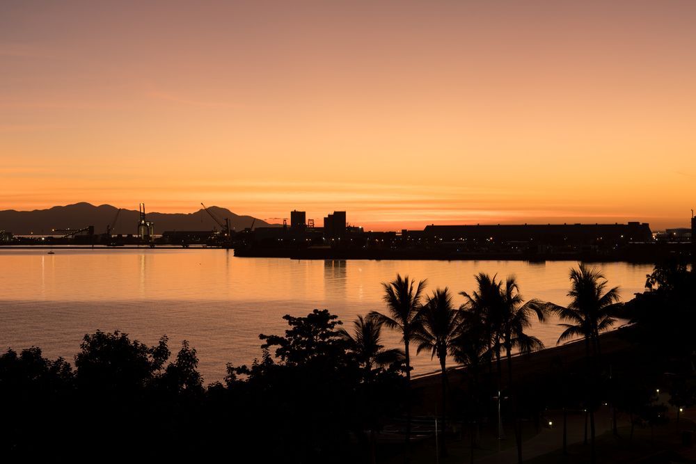 A Sunset Over A Body Of Water With Palm Trees In The Foreground — Life Legal in West End, QLD