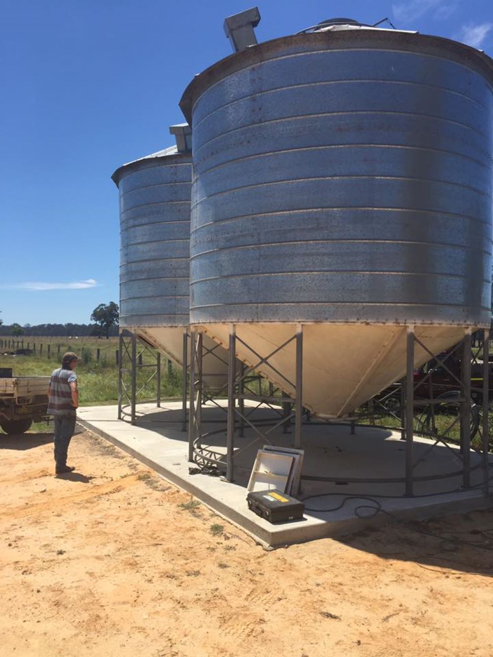 A Man is Standing in Front of a Row of Silos — Wallamore Grading & Packaging In Barraba, NSW