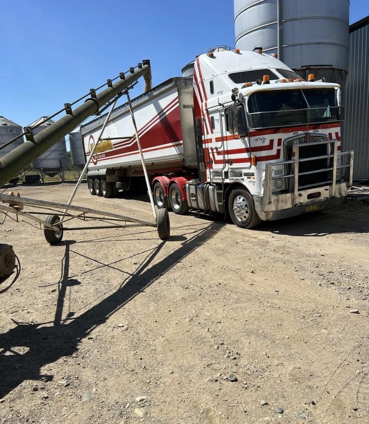 A Red and White Semi Truck is Parked in a Dirt Lot — Wallamore Grading & Packaging In Wallamore, NSW