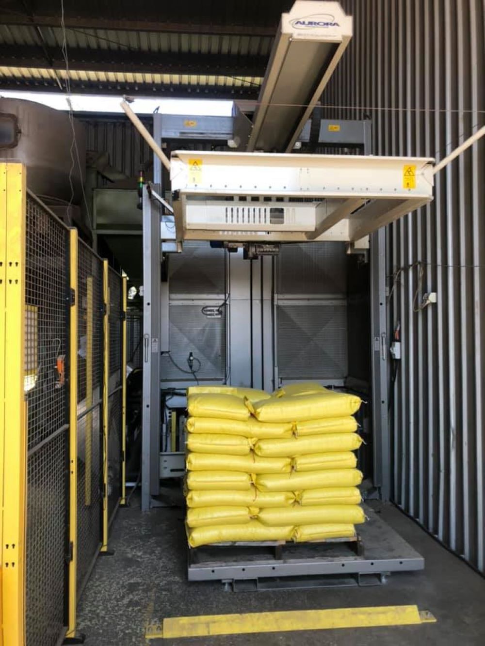 A Machine is Stacking Yellow Bags on a Pallet — Wallamore Grading & Packaging In Wallamore, NSW