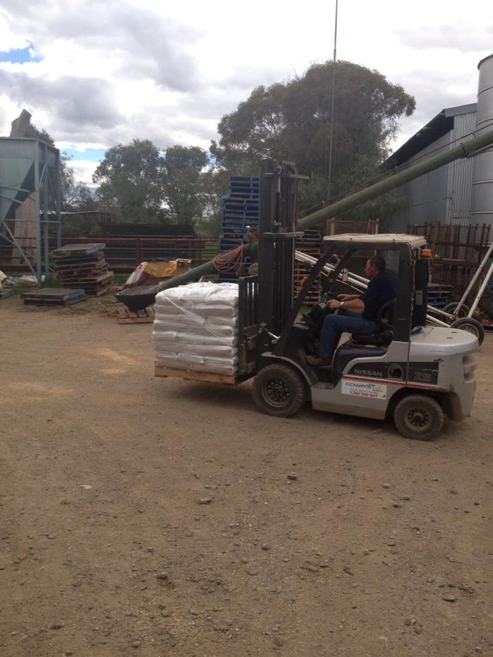 A Man is Driving a Forklift Carrying a Pallet of Bags — Wallamore Grading & Packaging In Wallamore, NSW