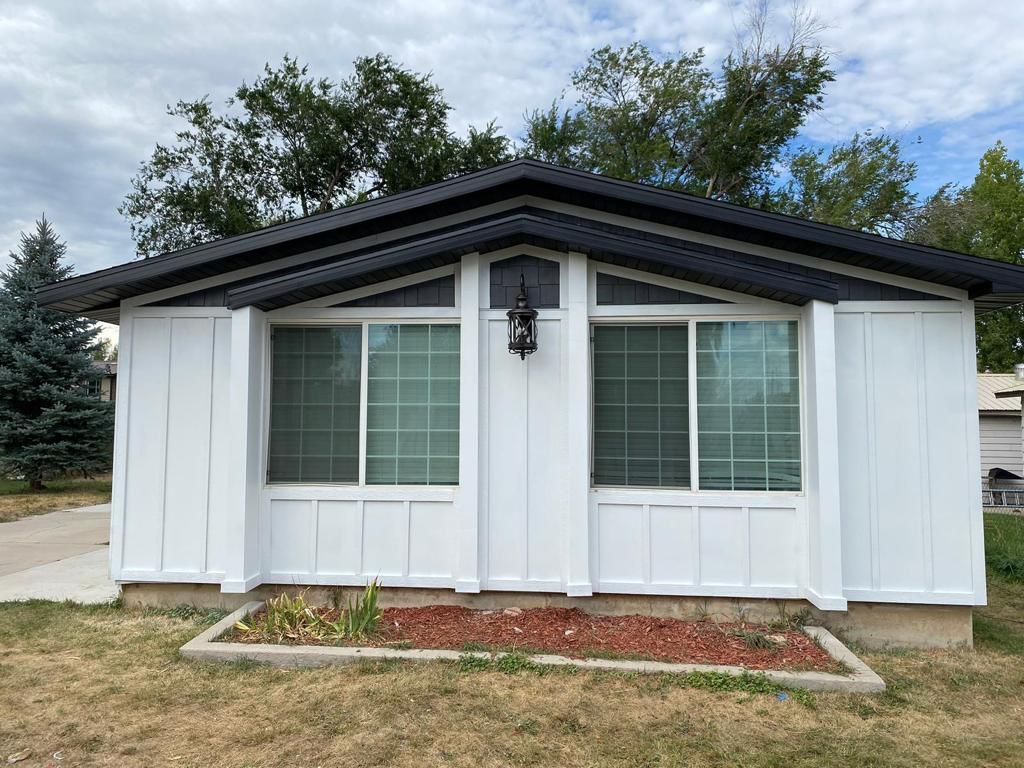 A woman is working on the underside of a car in a garage.