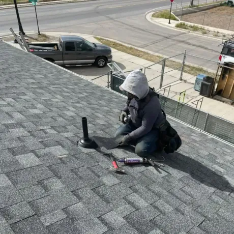 A man wearing a hard hat and safety glasses is working on a piece of metal.