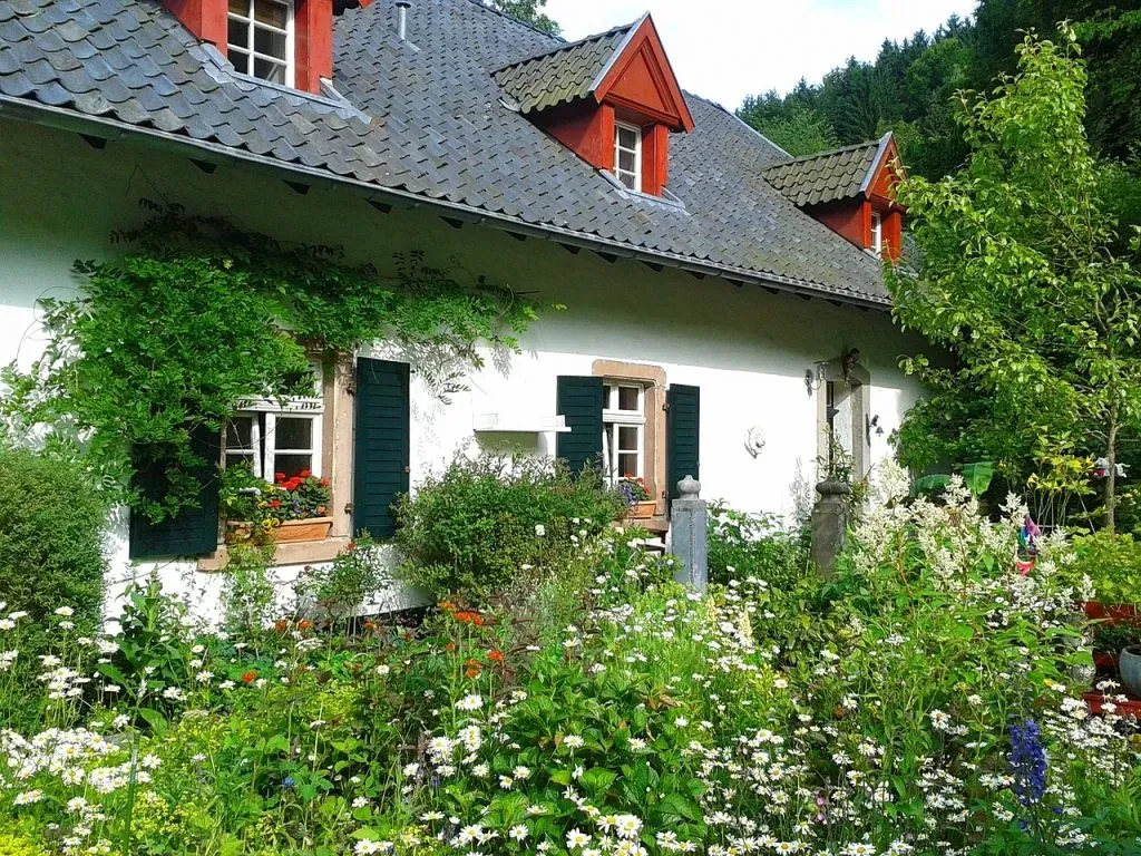 A white house with a red roof and green shutters