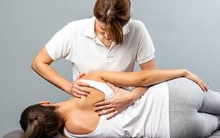 Female therapist manipulating shoulder blade on young female patient — Chiropractic Care Service in Eden Prairie, MN
