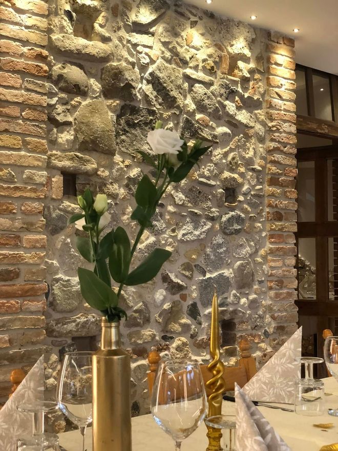 Un vaso dorato con un fiore bianco è appoggiato su un tavolo apparecchiato per la cena